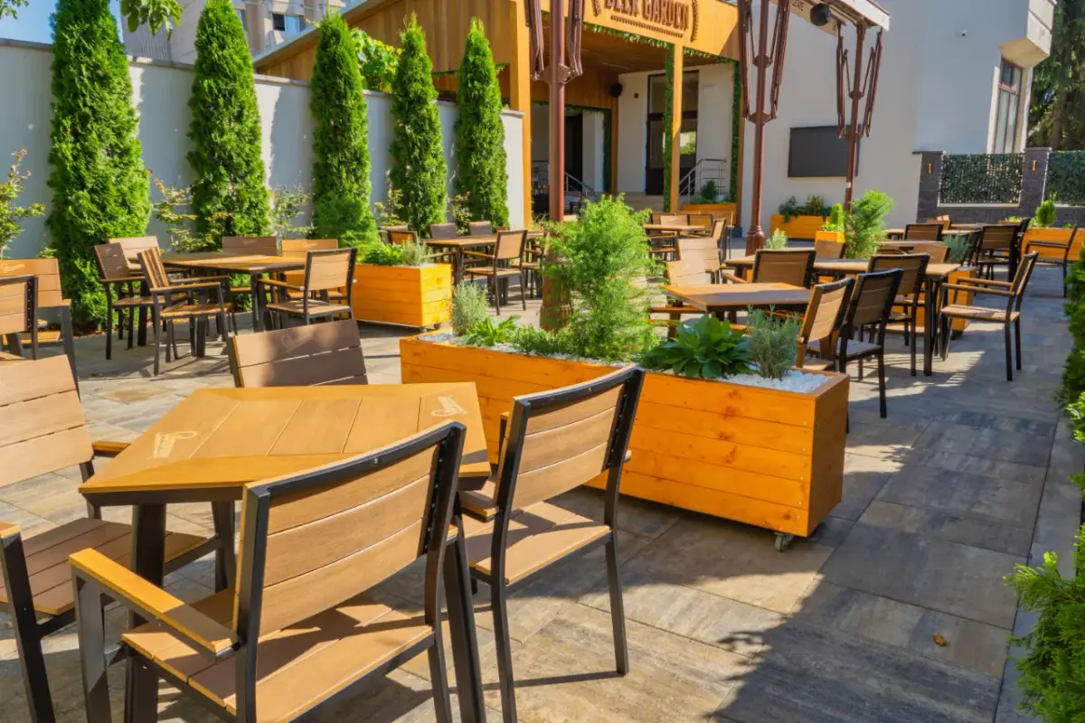 Terasa Beer Garden cu mese din lemn și verdeață