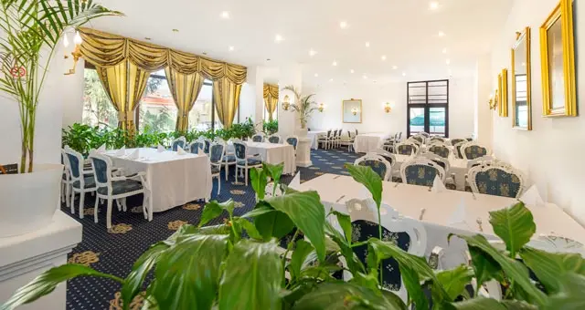 Salonul luminos al Restaurantului Hotel Cetate, cu mese aranjate și plante